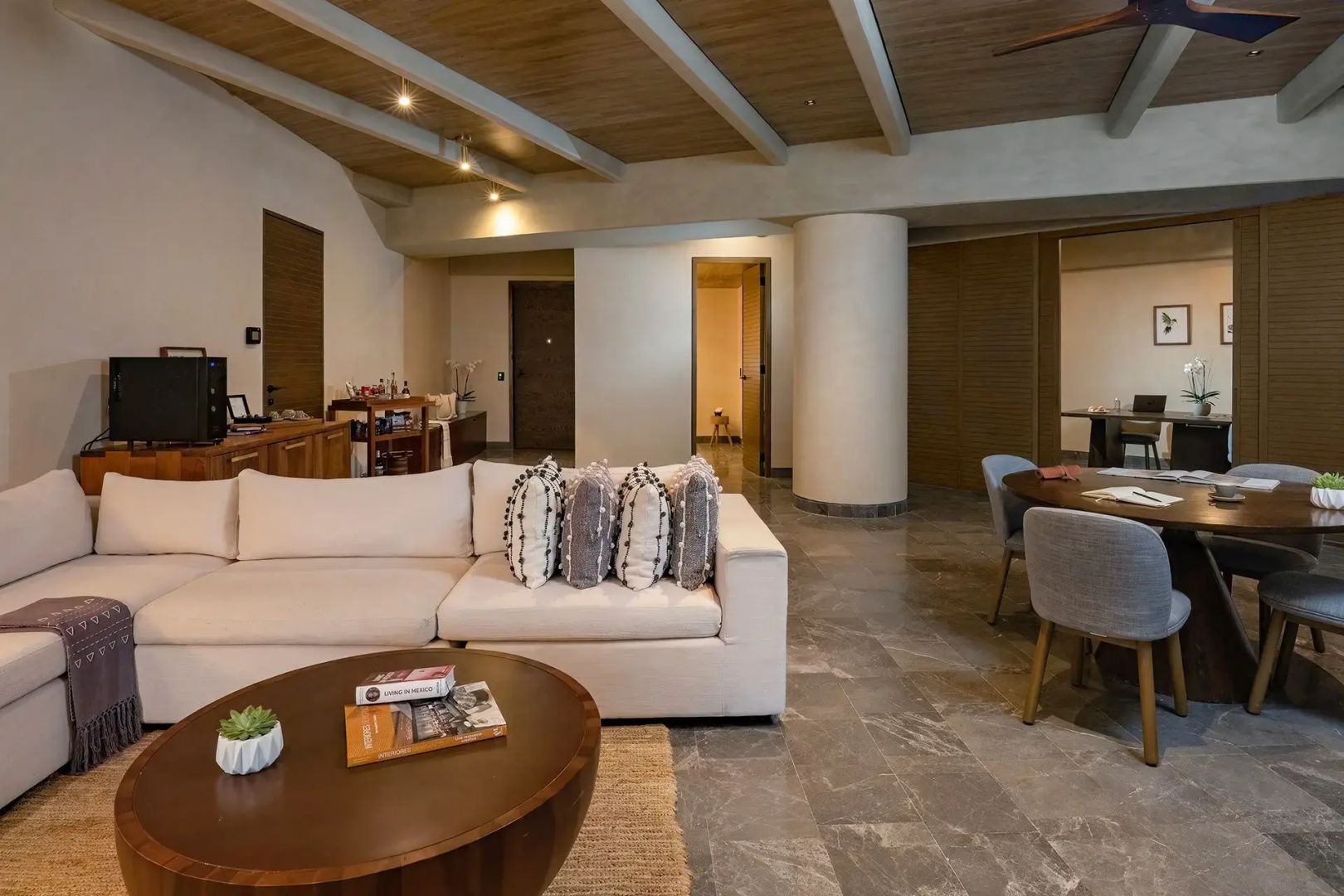 Wohnzimmer einer Suite mit hellem Ecksofa, Couchtisch aus Holz und hellem Fliesenboden.