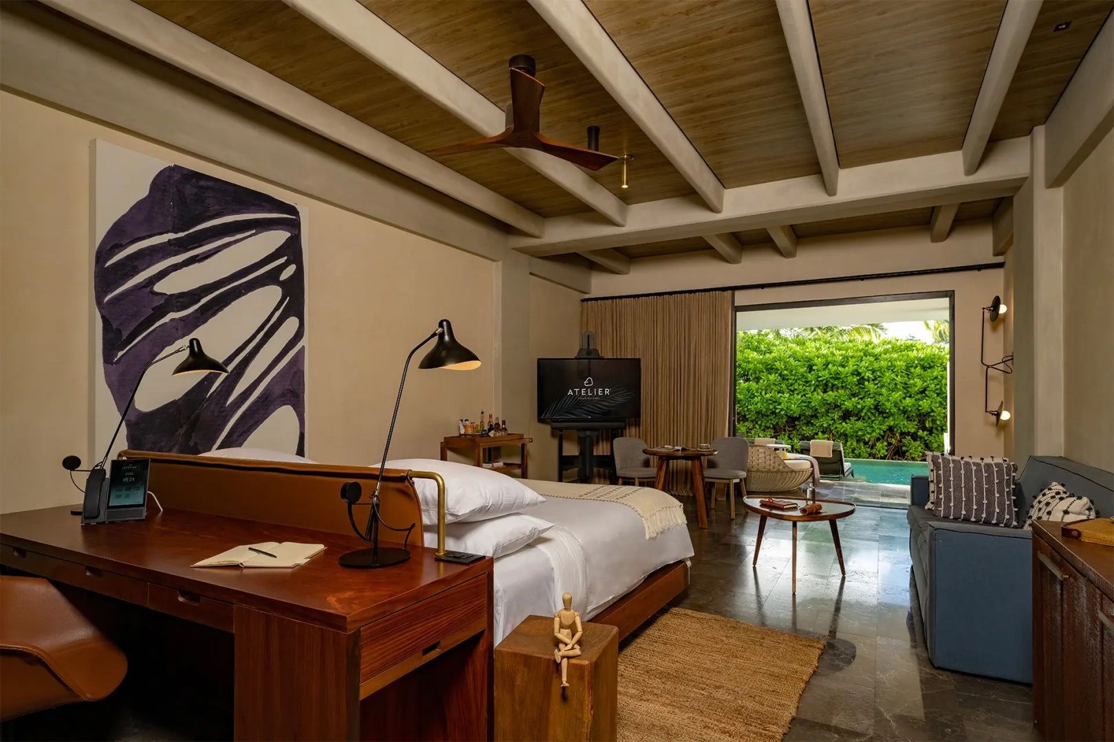 Hotelzimmer mit Holzschreibtisch, Doppelbett und Blick auf die Terrasse mit Pool.