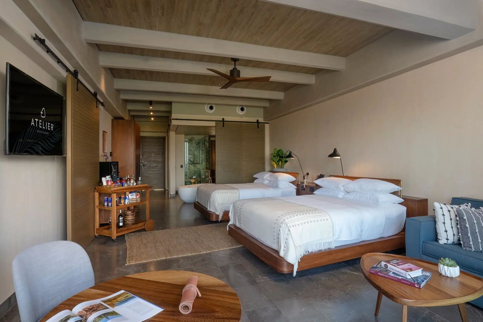 Hotelzimmer mit zwei Doppelbetten, Holzdecke mit Ventilator und Barwagen.