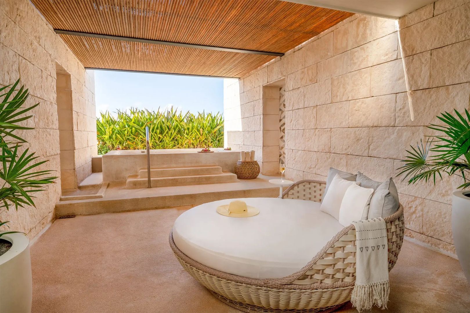 Überdachte Terrasse mit einem runden Tagesbett und integriertem Jacuzzi im Außenbereich.
