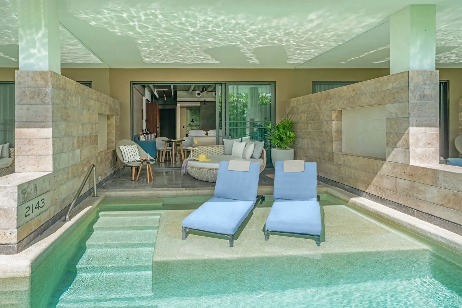 Swim-Up-Terrasse mit zwei blauen Liegestühlen im flachen Poolwasser.