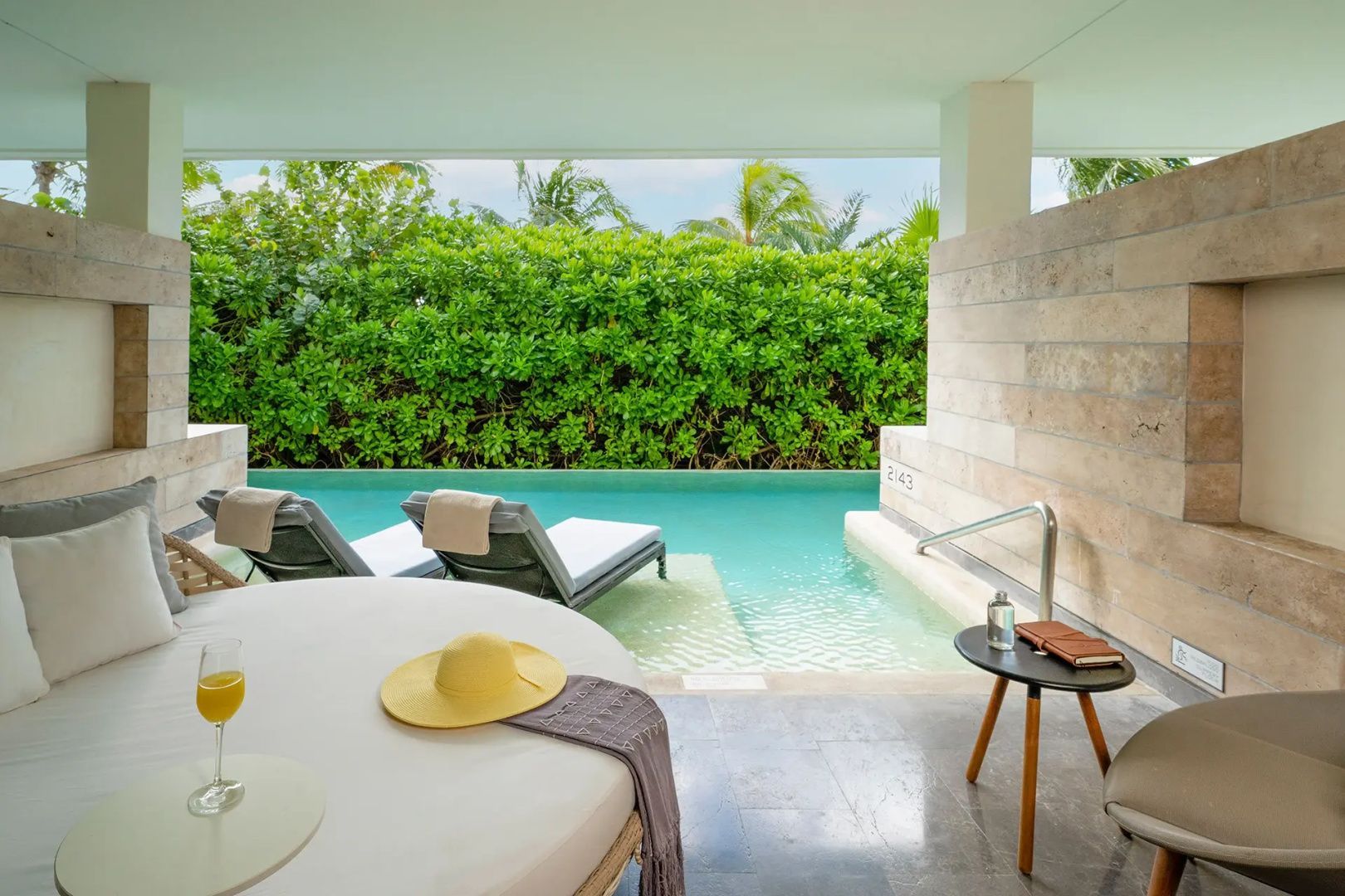 Terrasse einer Suite mit direktem Zugang zu einem privaten Pool und Sonnenliegen vor grünen Pflanzen.