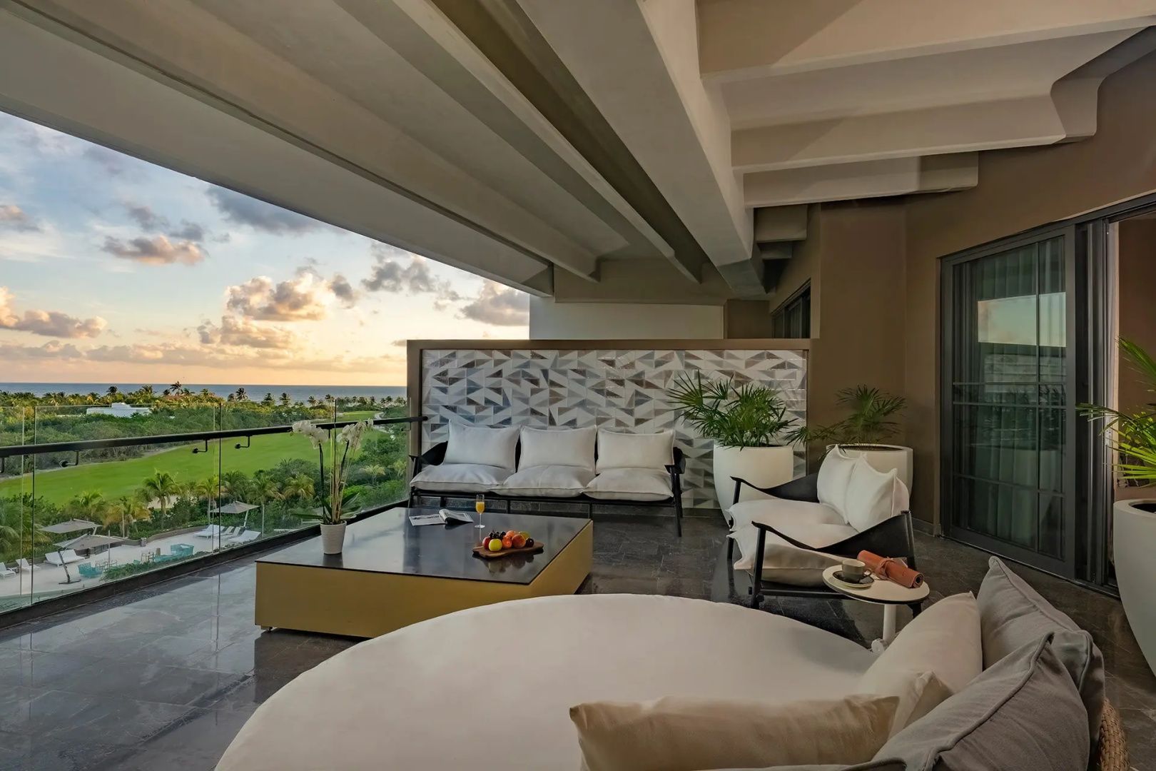 Überdachte Terrasse mit Sitzmöbeln und Blick auf die grüne Landschaft und das Meer.