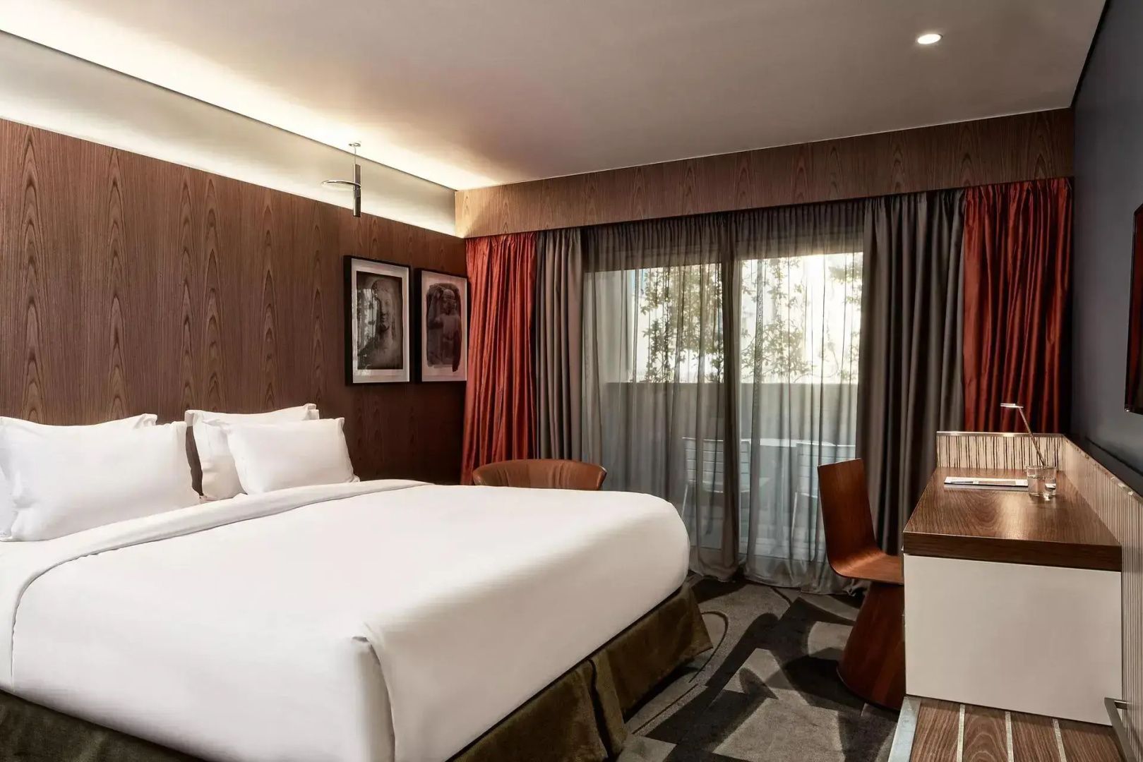 Hotelzimmer mit Doppelbett, dunkler Holzverkleidung und Zugang zum Balkon