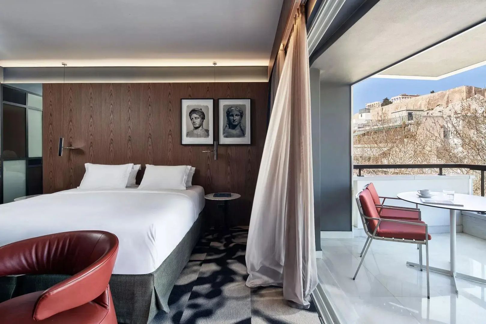Hotelzimmer mit weißem Doppelbett, Holzwand und Zugang zum Balkon.