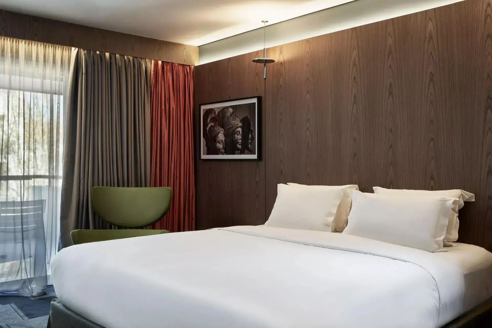 Doppelbett mit weißer Bettwäsche vor einer dunklen Holzvertäfelung im Hotelzimmer.