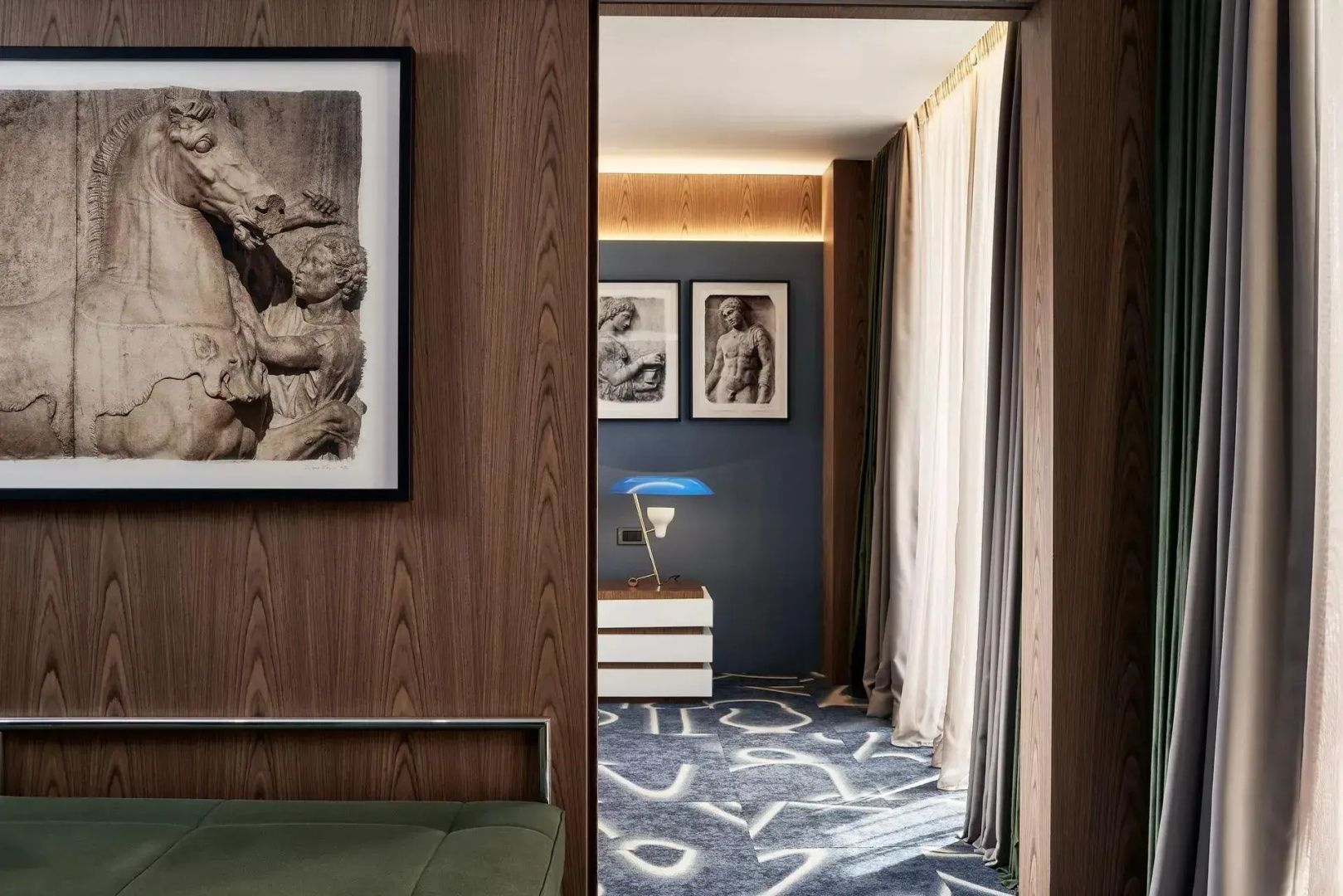 Blick durch eine Holzvertäfelung in ein Hotelzimmer mit gemustertem Teppich.