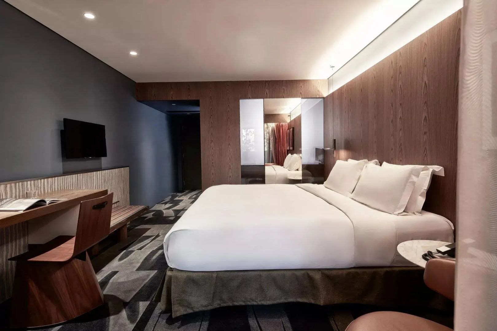 Geräumiges Hotelzimmer mit Doppelbett, Holzpaneelen und Schreibtisch