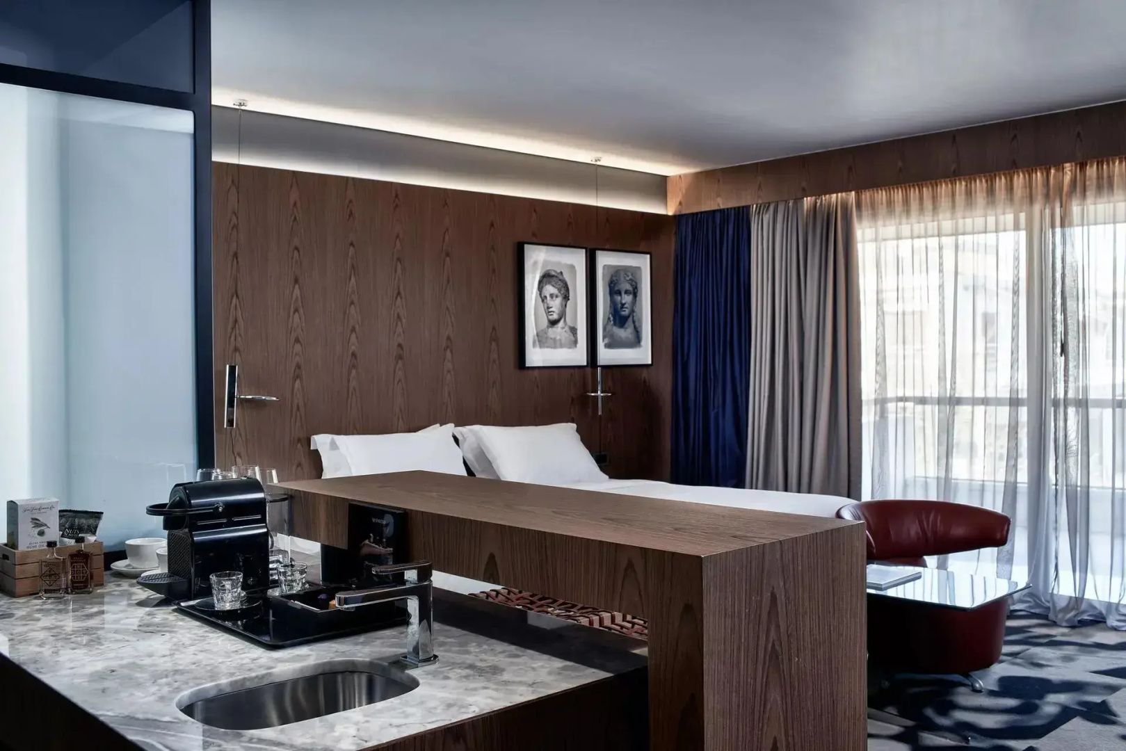 Zimmerbereich mit kleiner Kitchenette im Vordergrund und Doppelbett im Hintergrund.