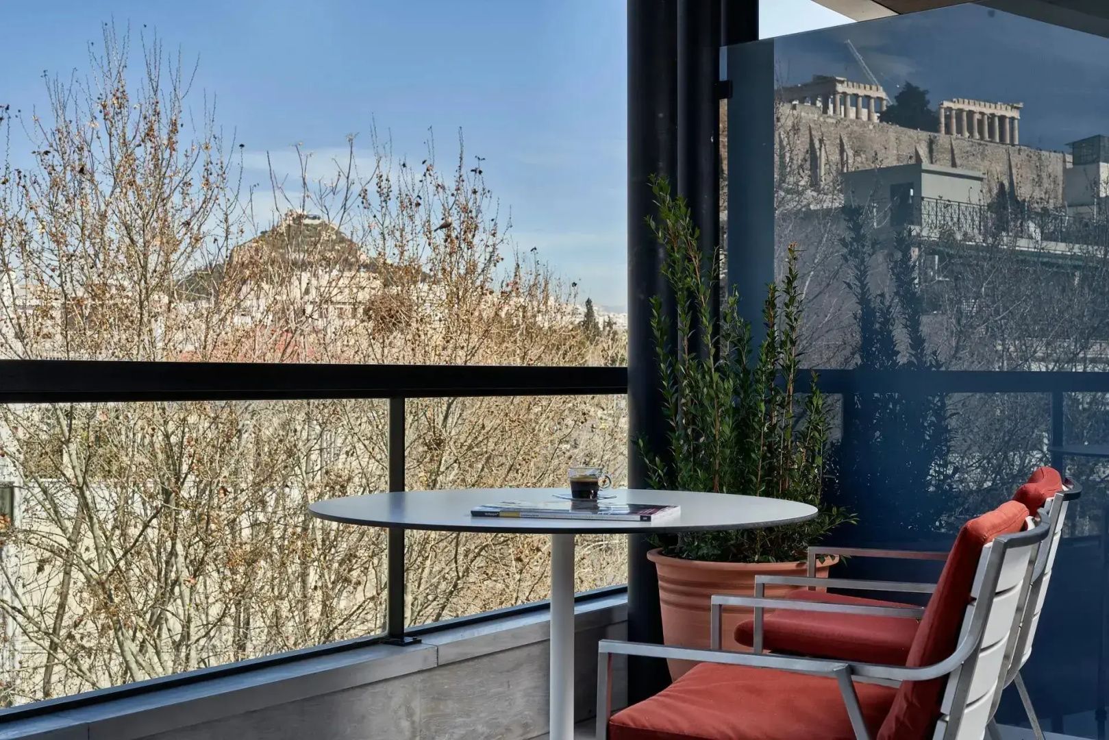 Hotelbalkon mit Sitzgelegenheiten und Aussicht auf die Stadt und Hügel.