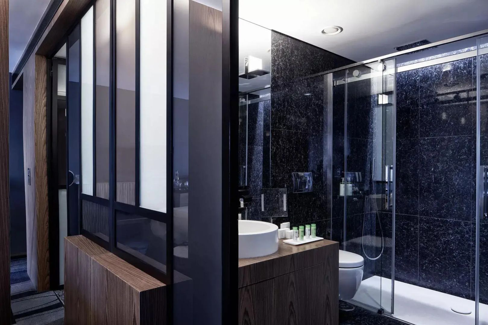 Badezimmer mit schwarzer Duschkabine und weißem Aufsatzwaschbecken auf Holzschrank.