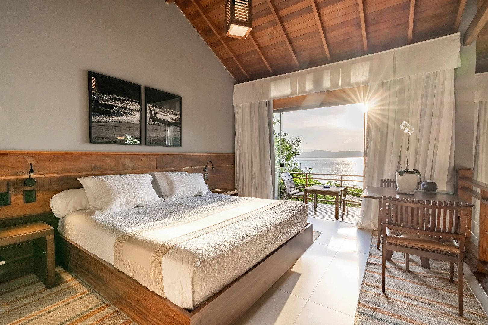 Schlafzimmer mit Doppelbett, Holzdecke und Ausgang zur Terrasse mit Meerblick.