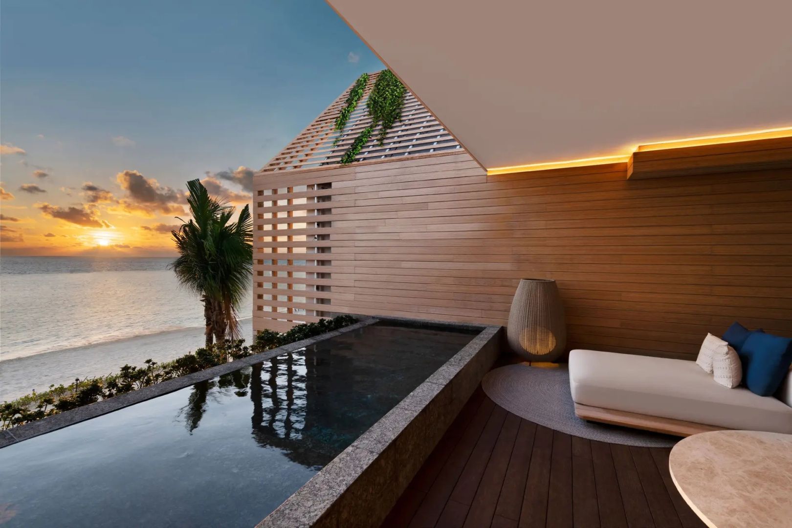 Privater Pool auf einer Holzterrasse vor dem Strand bei abendlicher Dämmerung.