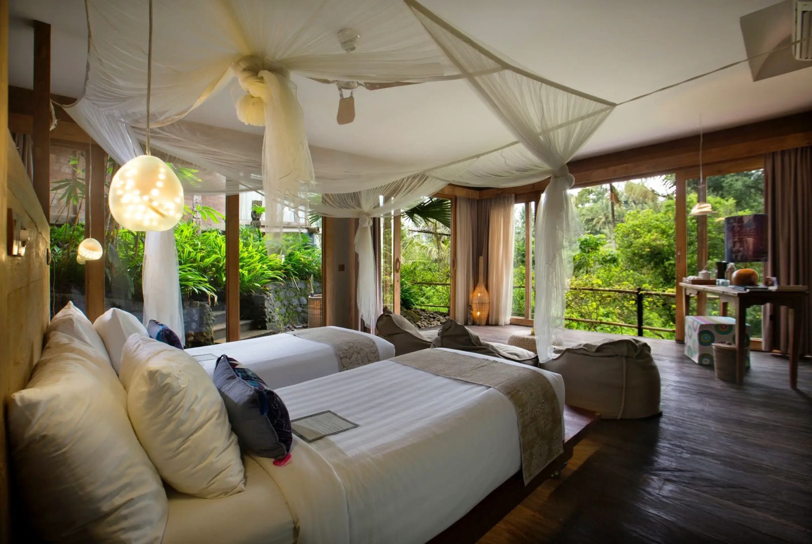 Helles Zimmer mit zwei Einzelbetten, Moskitonetz und bodentiefen Glasfronten zum Garten.