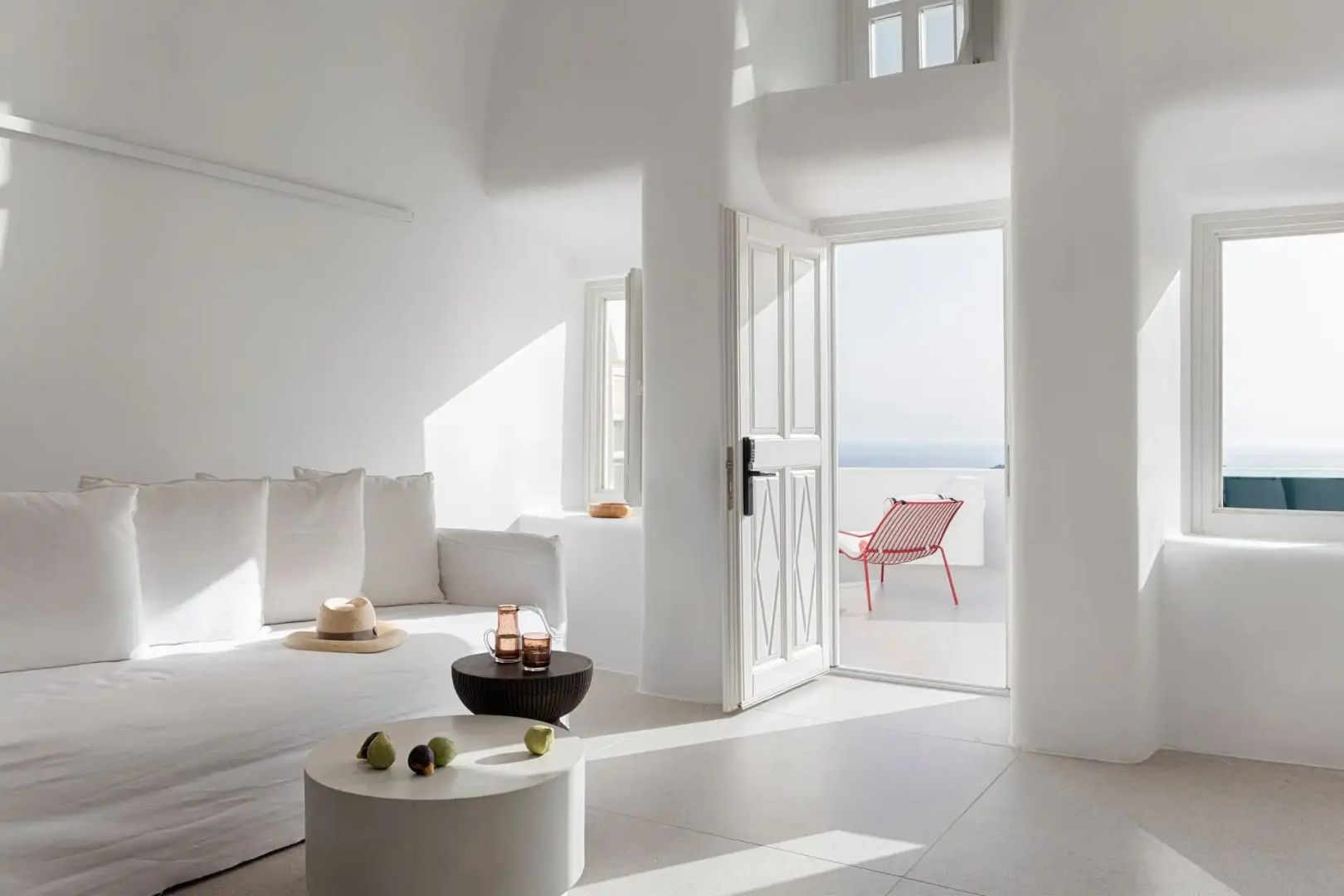Lichtdurchfluteter Wohnbereich mit weißem Sofa und Tür zur Terrasse mit Meerblick.