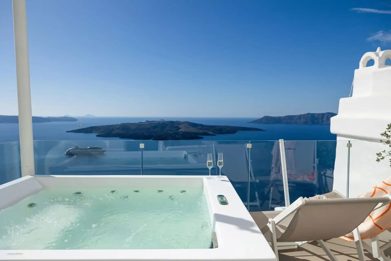 Whirlpool auf einer Terrasse mit Glasgeländer und Panoramablick auf das Meer und Inseln.