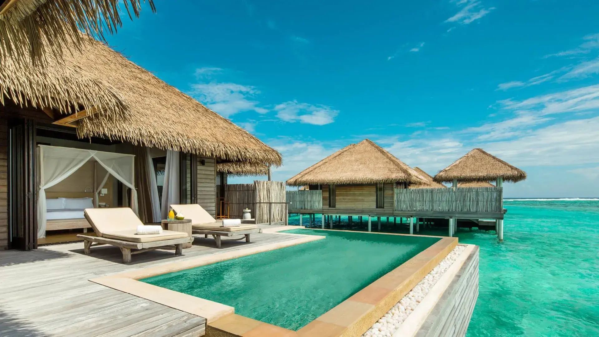 Privater Pool auf der Holzterrasse einer Wasservilla mit Blick auf das Meer.