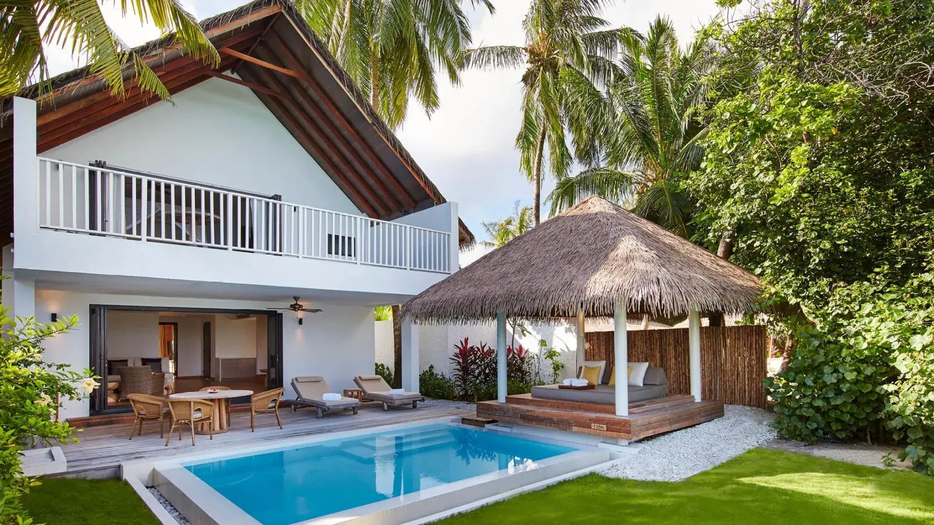 Außenansicht einer Villa mit eigenem Pool, Gartenpavillon und Palmen.