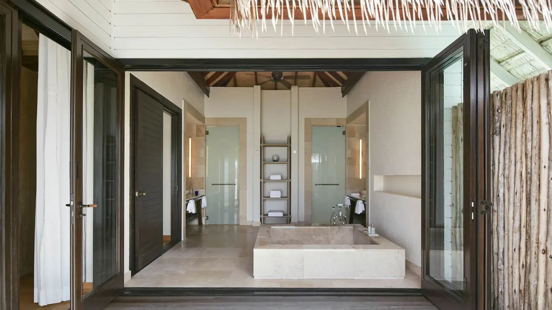 Badezimmer einer Villa mit großer eckiger Steinbadewanne und Glastüren.