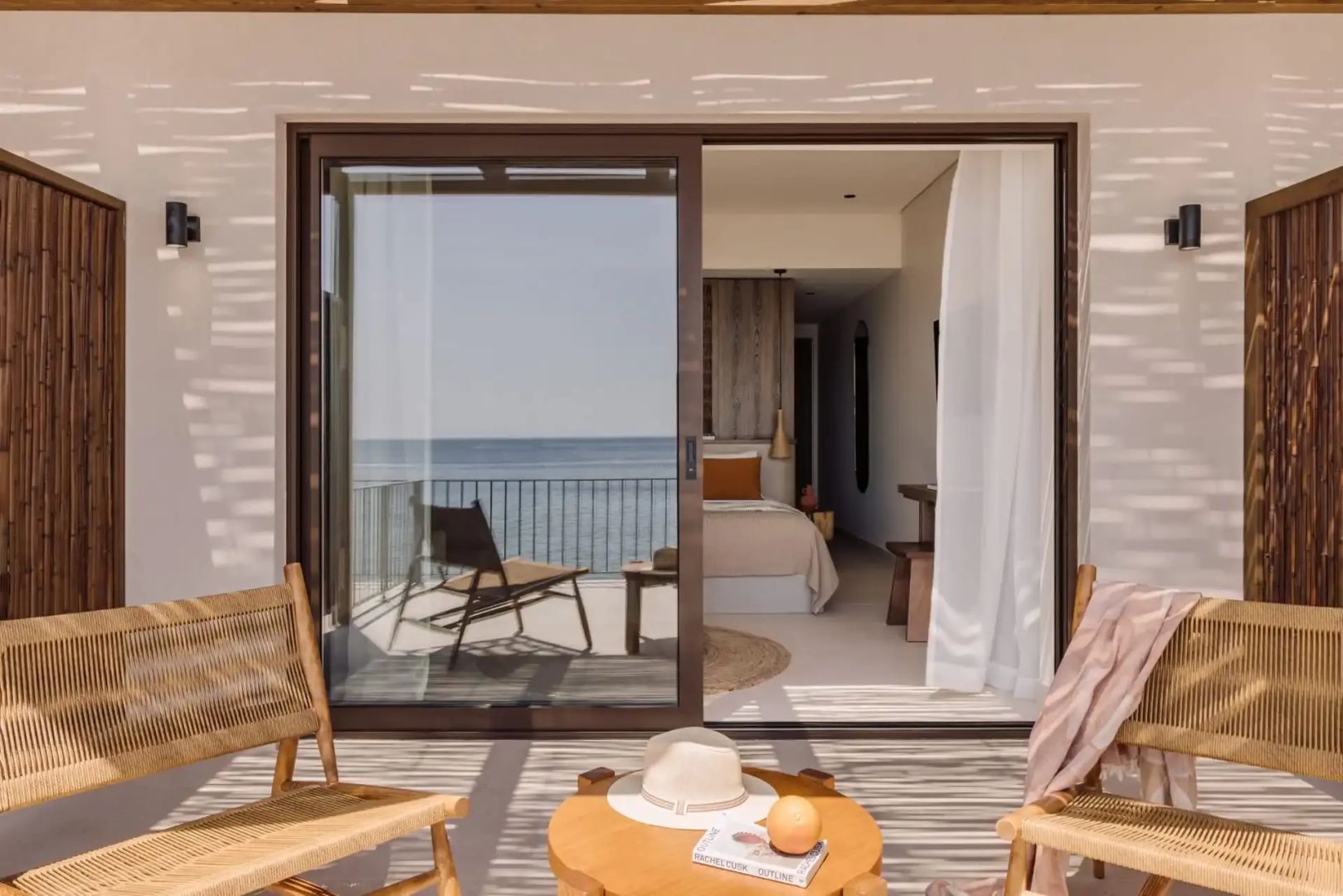 Balkon mit Holzstühlen, einem kleinen Tisch und Blick auf das blaue Meer.