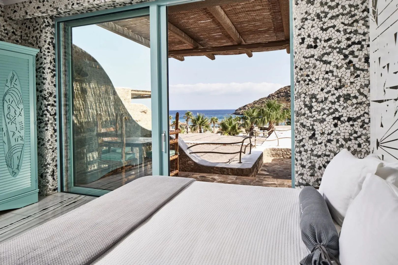 Blick aus dem Schlafzimmer über die Terrasse auf Palmen und das Meer.