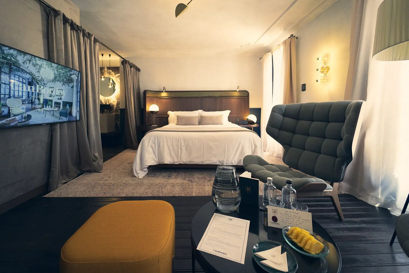 Großes Doppelbett in einer Suite mit gepolstertem Sessel und Couchtisch