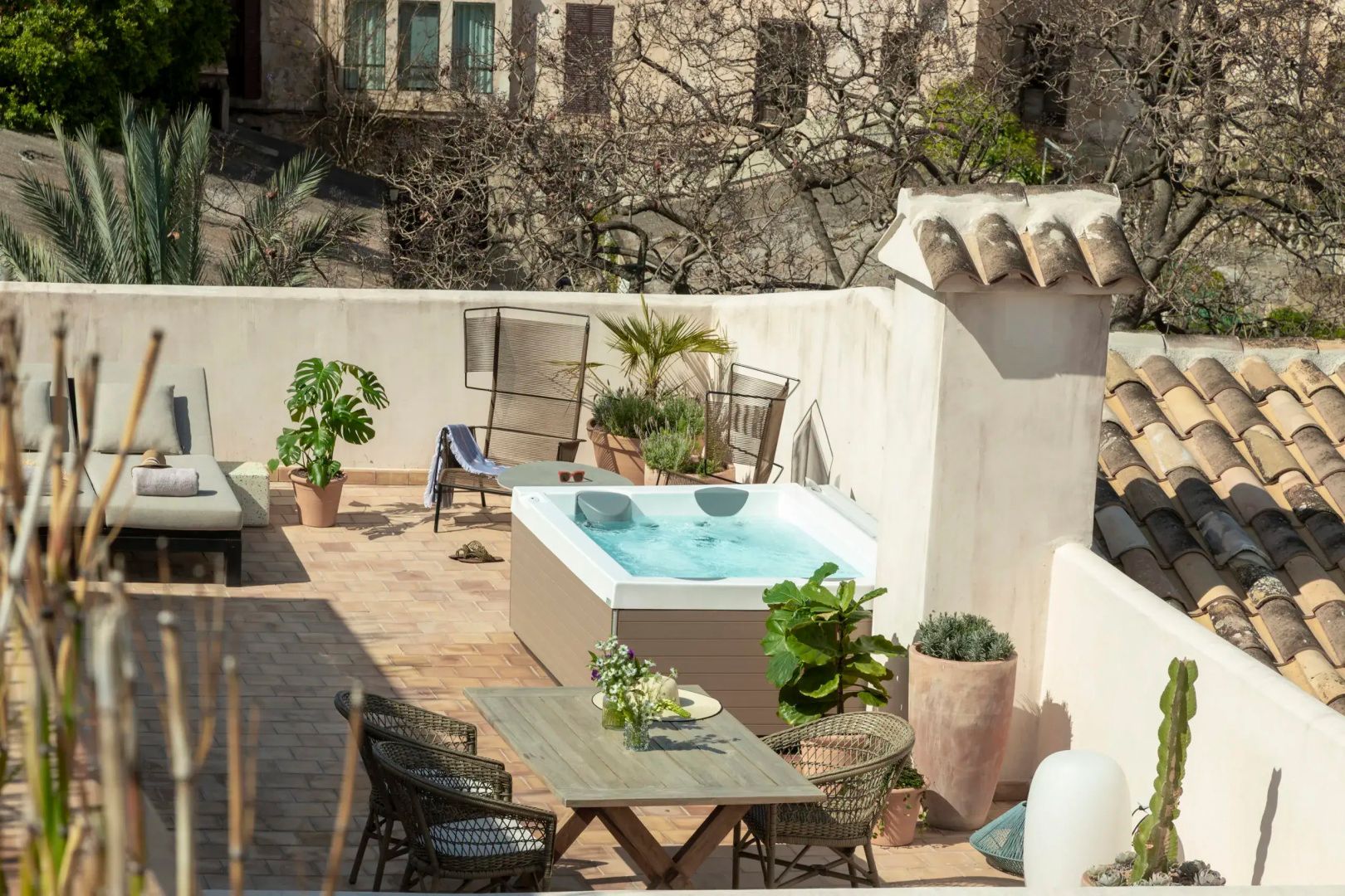 Dachterrasse mit Whirlpool, Esstisch, Stühlen und verschiedenen Topfpflanzen