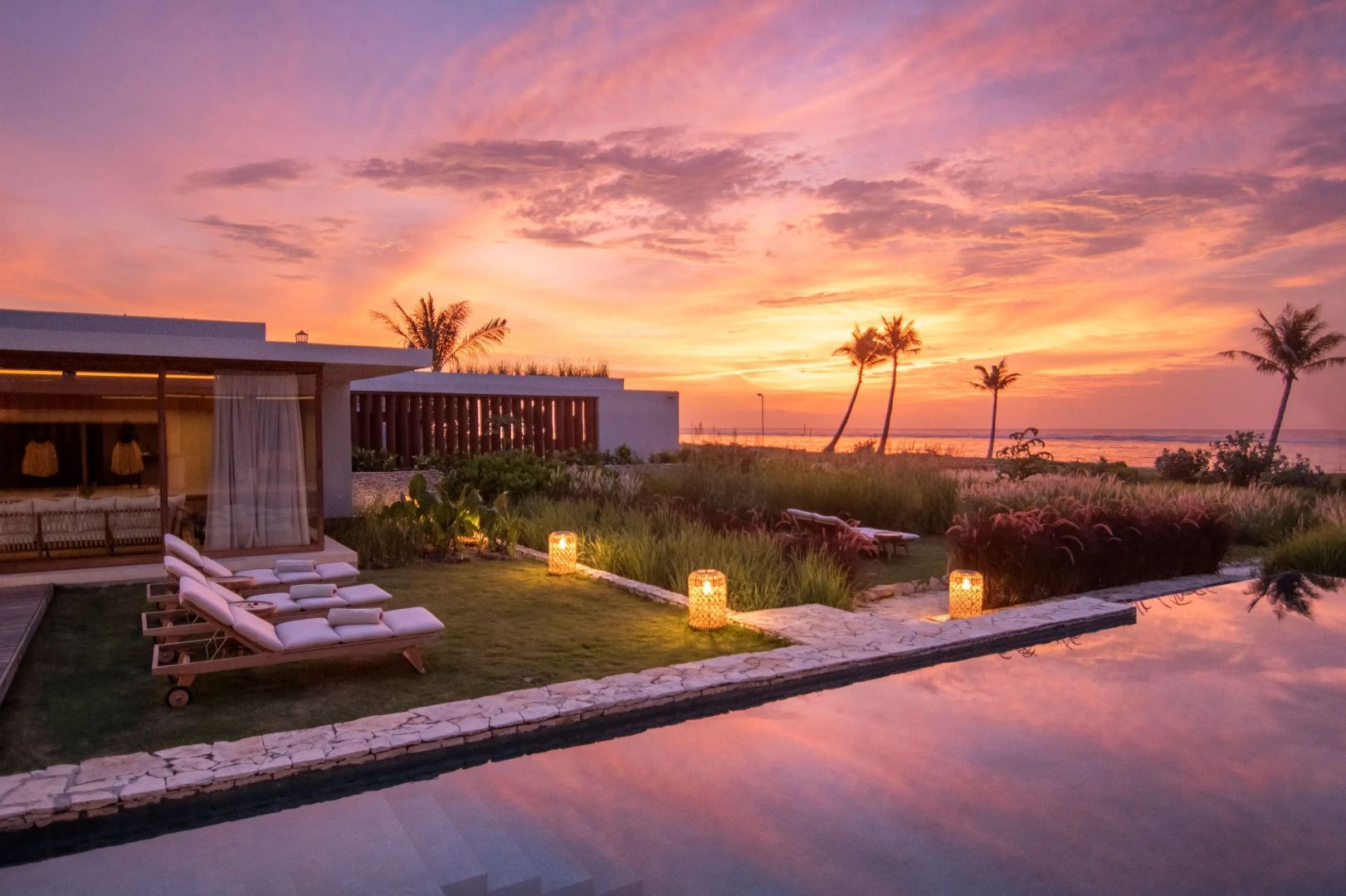 Villa mit Garten und Pool im Abendlicht bei Sonnenuntergang am Meer.