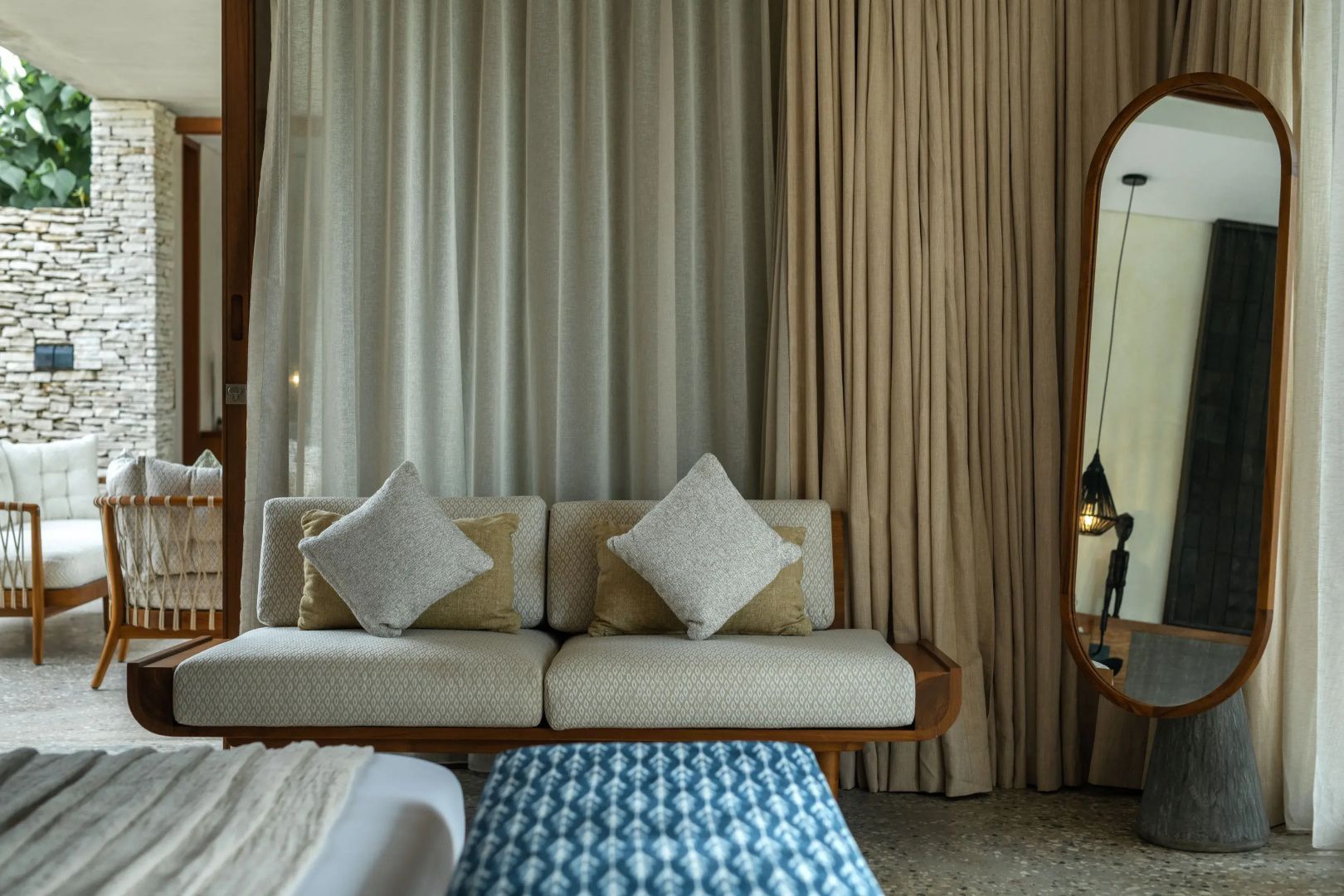 Sitzbereich im Zimmer mit bequemem Sofa, hellen Kissen und gemustertem Hocker