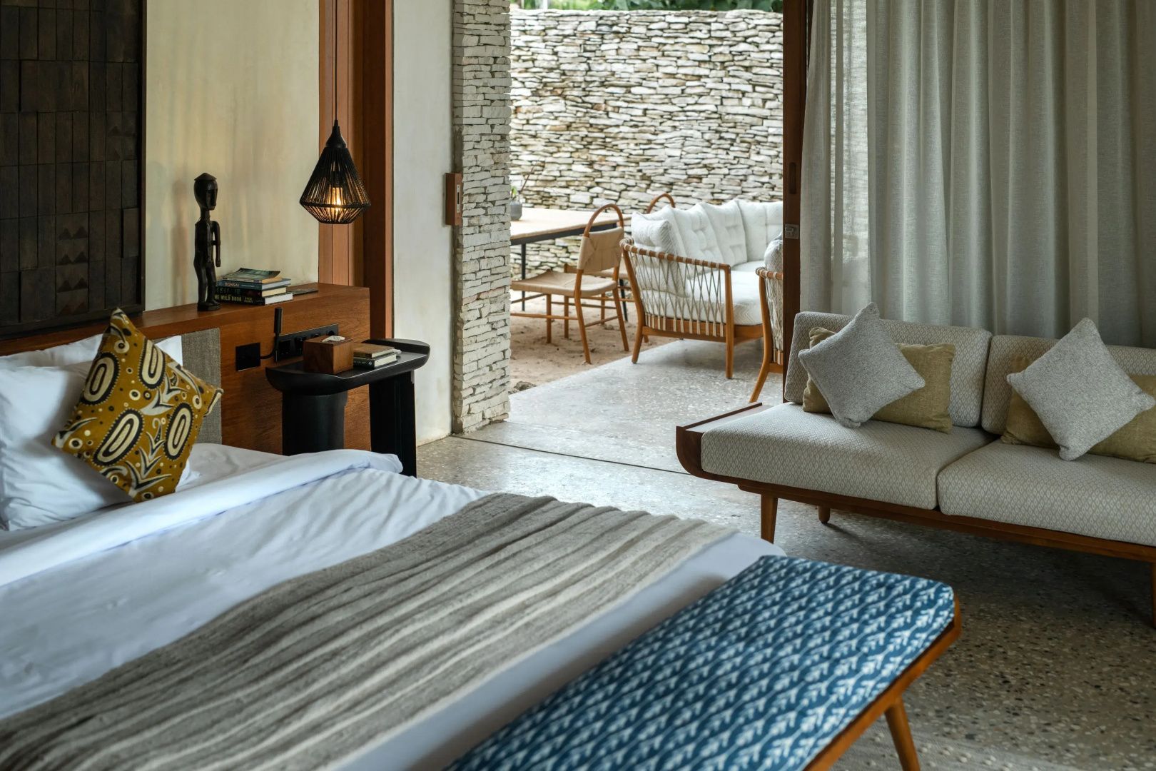 Helles Schlafzimmer mit Doppelbett, blauem Hocker und Zugang zur Terrasse