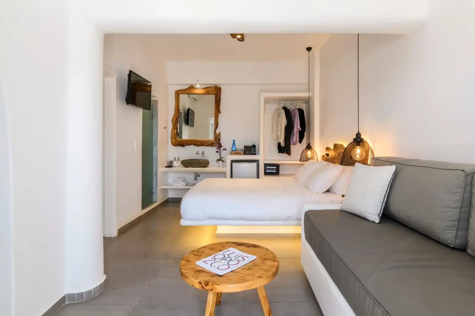 Geräumige Suite mit Doppelbett, Sitzbereich, Holztisch und offenem Kleiderschrank.