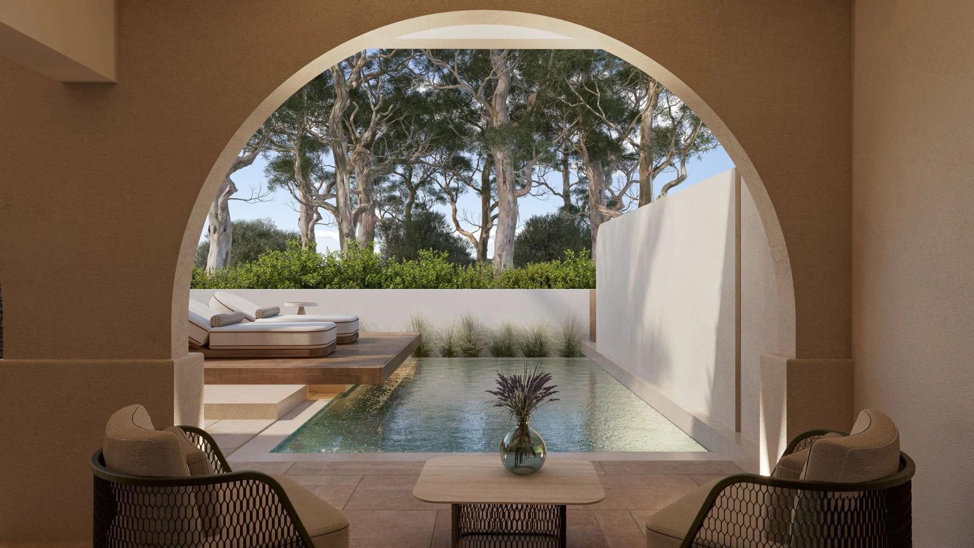 Blick durch einen Rundbogen auf eine Terrasse mit privatem Pool und Bäumen dahinter.