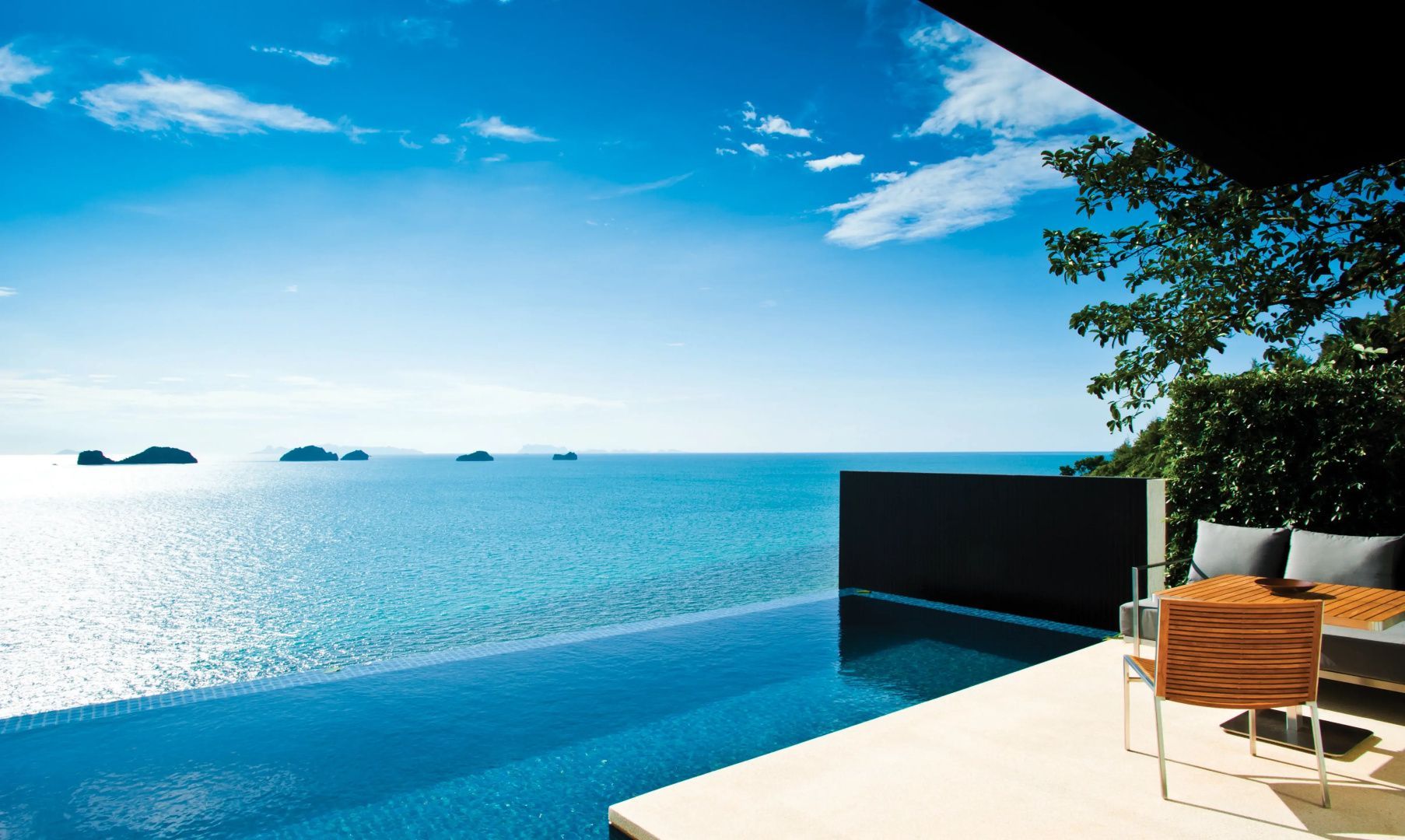 Infinity Pool an einer Terrasse mit direktem Blick auf das blaue Meer und kleine Inseln.