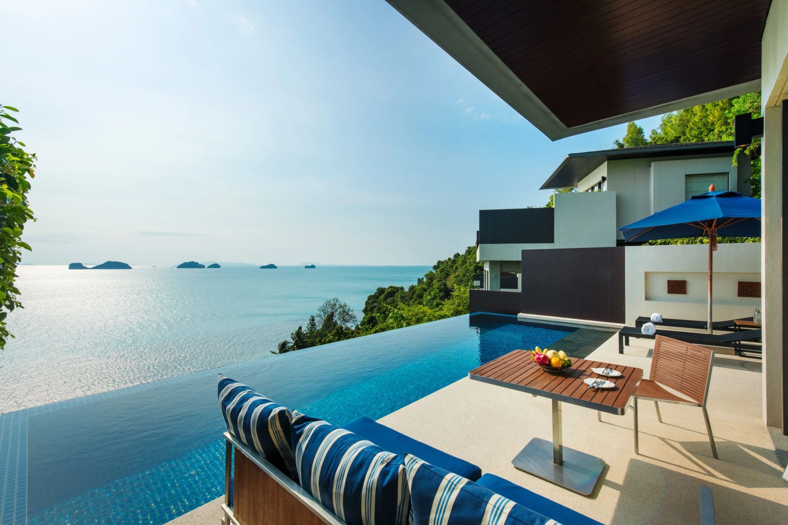 Terrassenbereich einer Villa mit Infinity Pool, Sitzmöbeln und Blick auf das Meer.