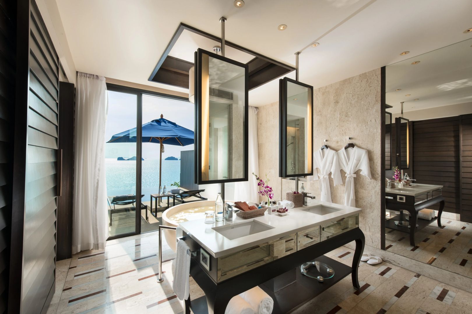 Badezimmer mit Waschtisch, freistehender Wanne und Terrasse mit Blick auf das Meer.