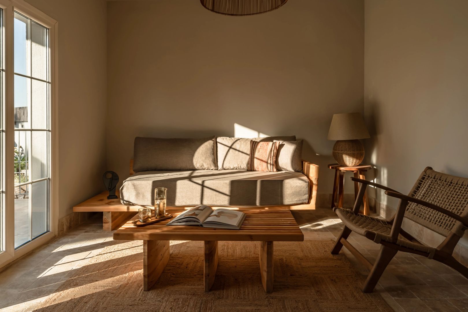 Sitzbereich im Hotelzimmer mit Sofa, Holzcouchtisch und Stuhl im Sonnenlicht.