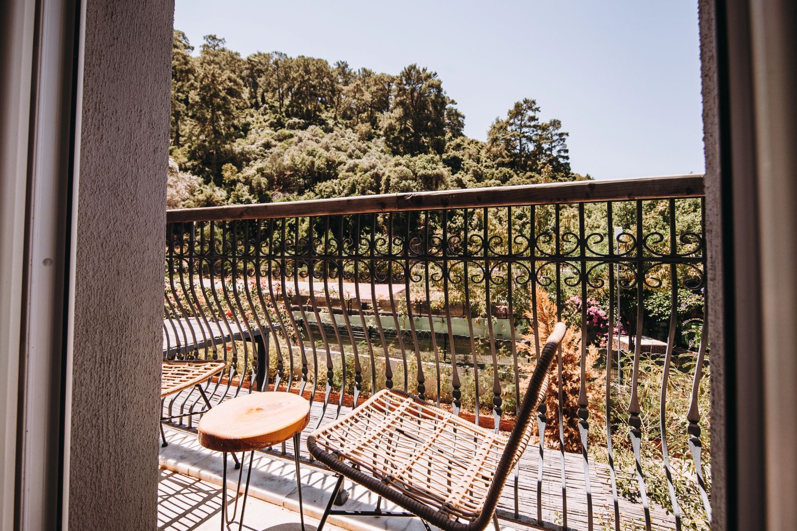 Balkon mit geschmiedetem Geländer, einem Stuhl und Ausblick auf bewaldete Hügel.