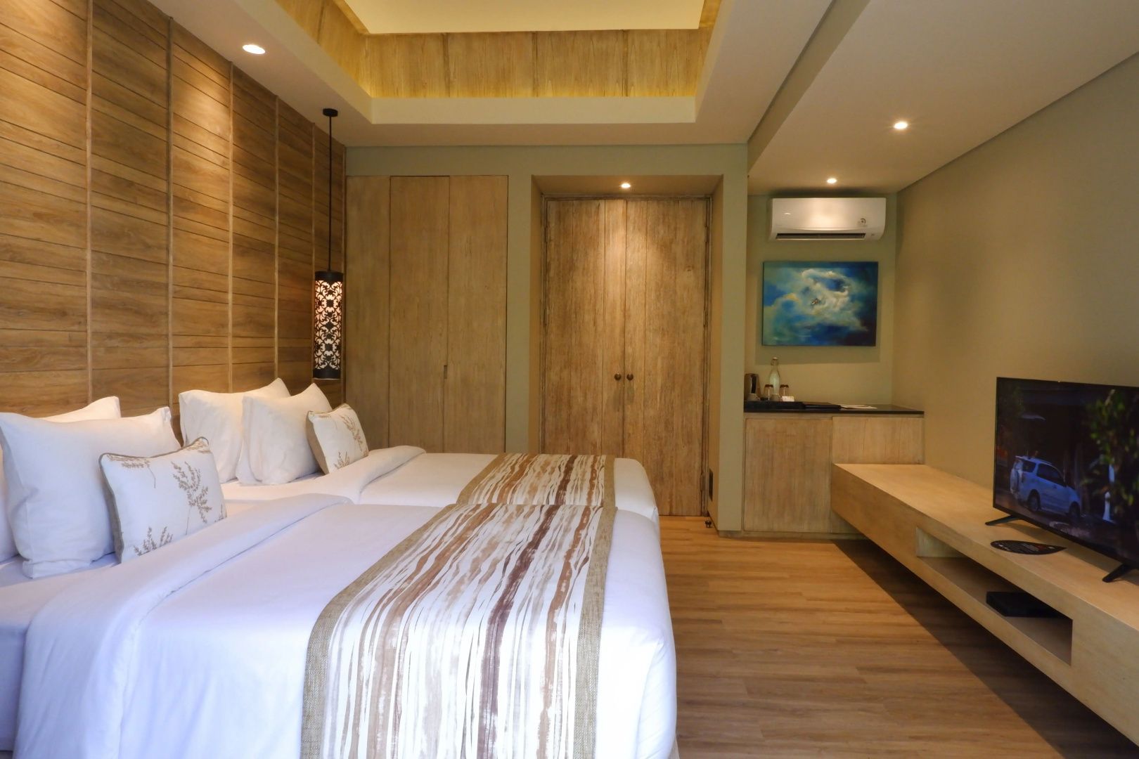 Blick in ein Hotelzimmer mit großen Holzschränken, Betten und hellen Wänden.