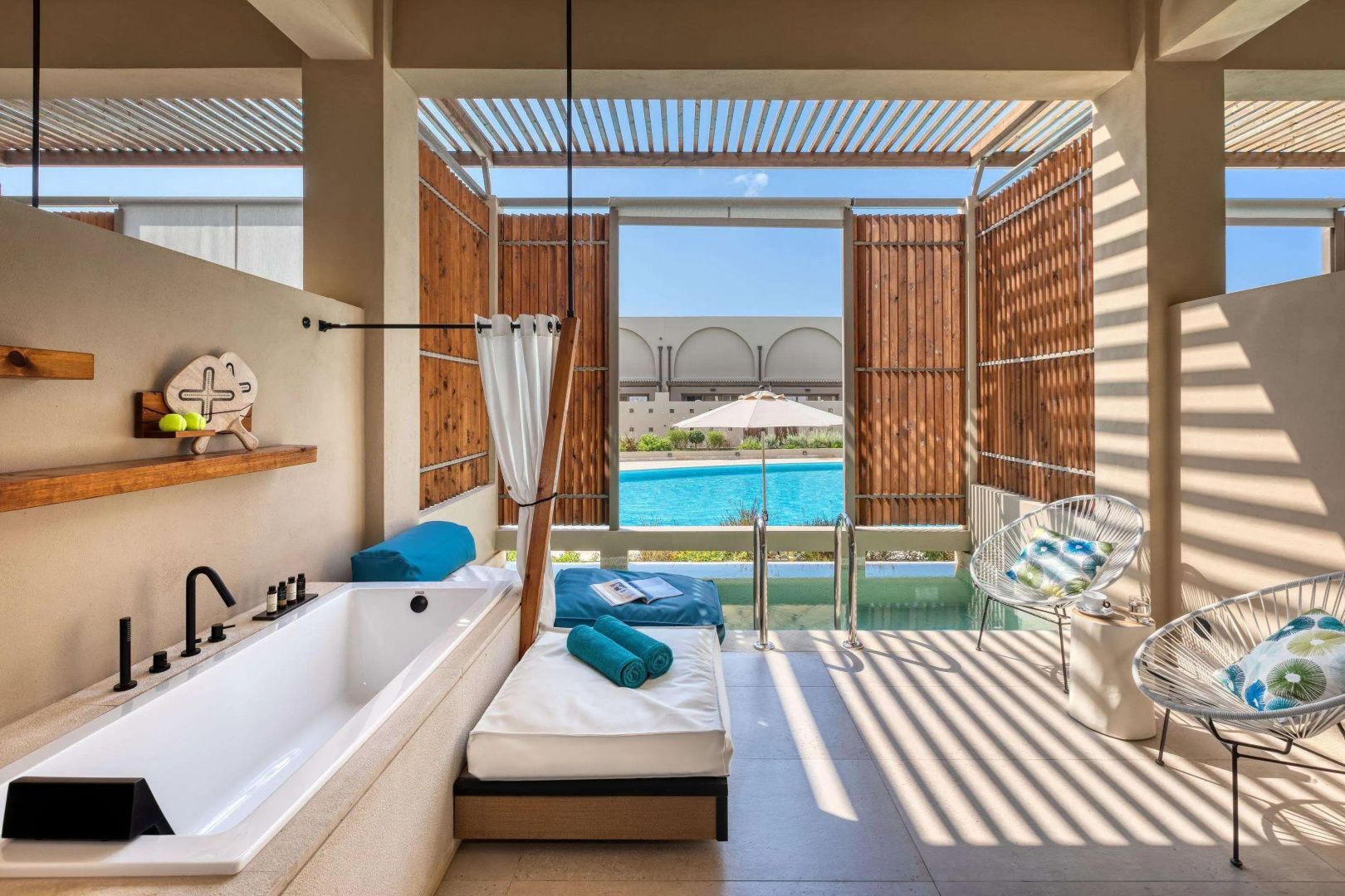 Überdachte Terrasse mit Badewanne, Liegebett und direktem Blick auf den Außenpool.