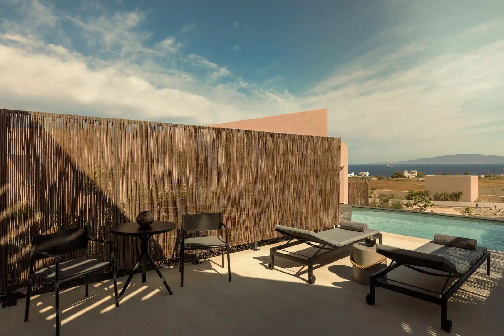 Terrasse mit Sonnenliegen, Schilf Sichtschutz und Ausblick auf das Meer.