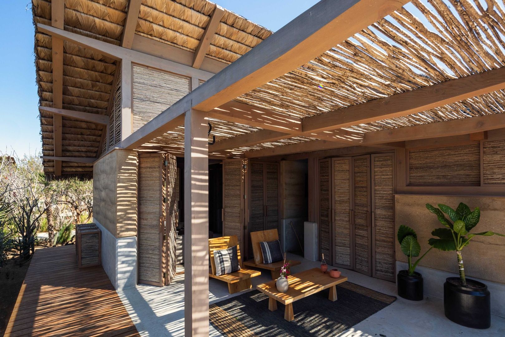 Terrasse aus Holzkonstruktion mit zwei Holzstühlen und Schattendach.