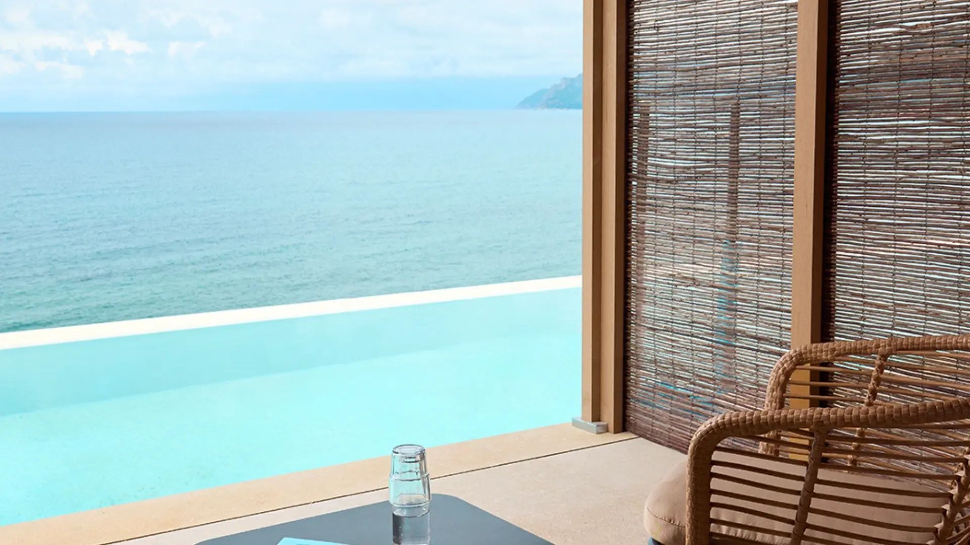 Blick von der überdachten Terrasse auf einen Infinity Pool und das offene Meer.