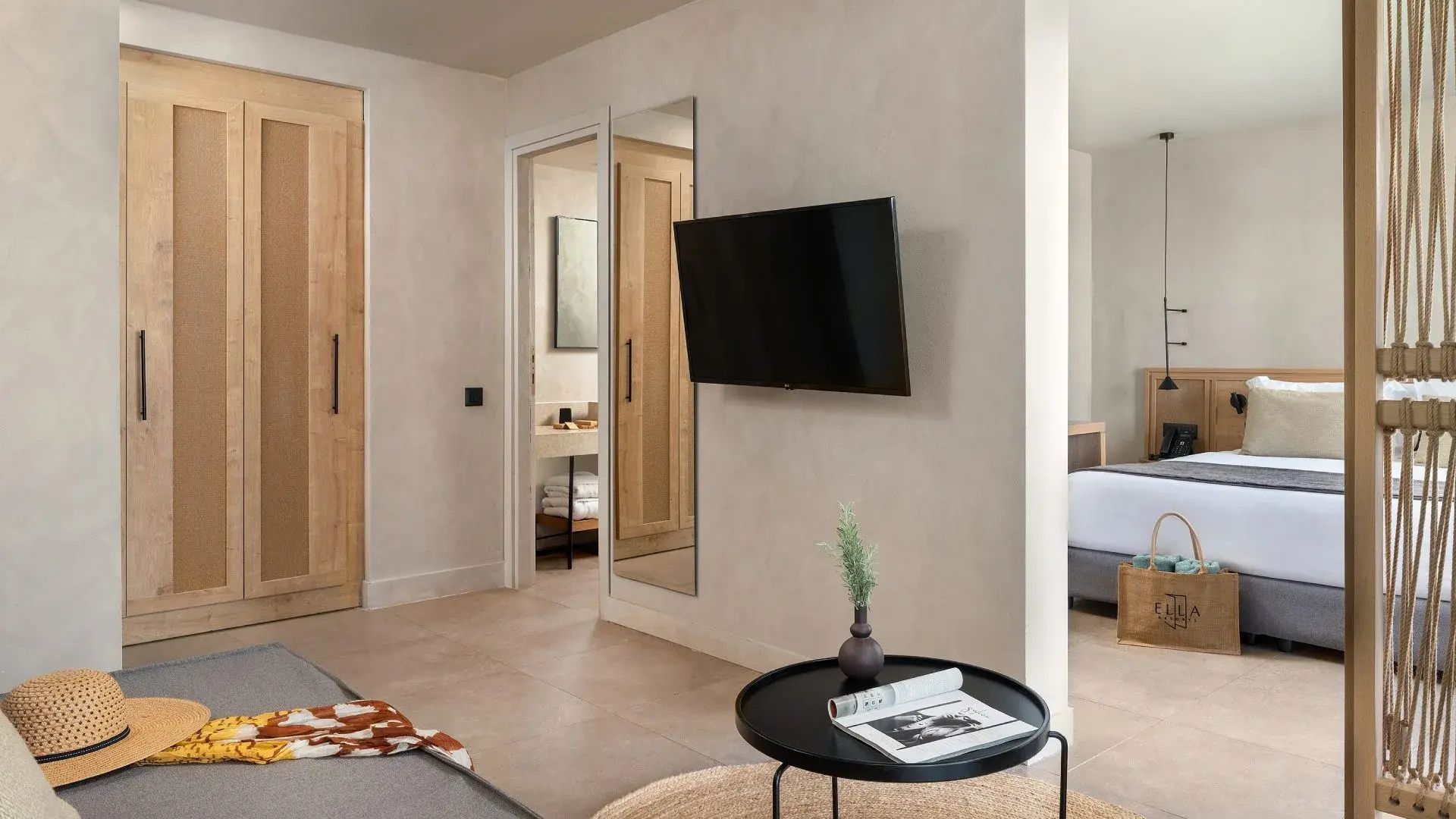 Hotelzimmer mit einem Fernseher an der Wand, Spiegel und Blick in das Badezimmer.