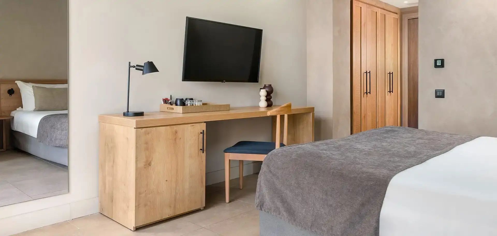 Schreibtisch aus Holz mit Stuhl und einem an der Wand montierten Flachbildfernseher.