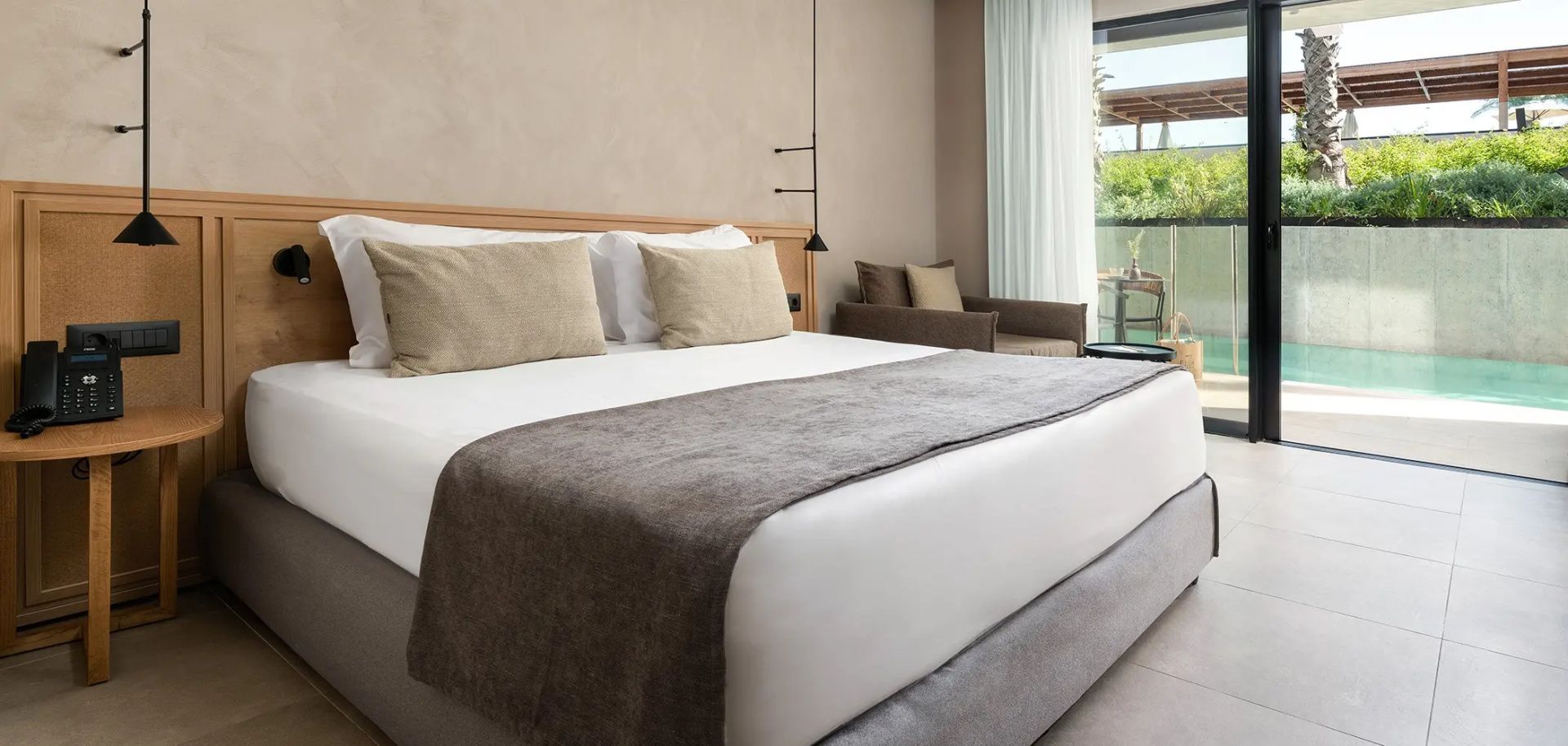 Doppelbett mit hellen Kissen und brauner Tagesdecke in einem modern gestalteten Zimmer.