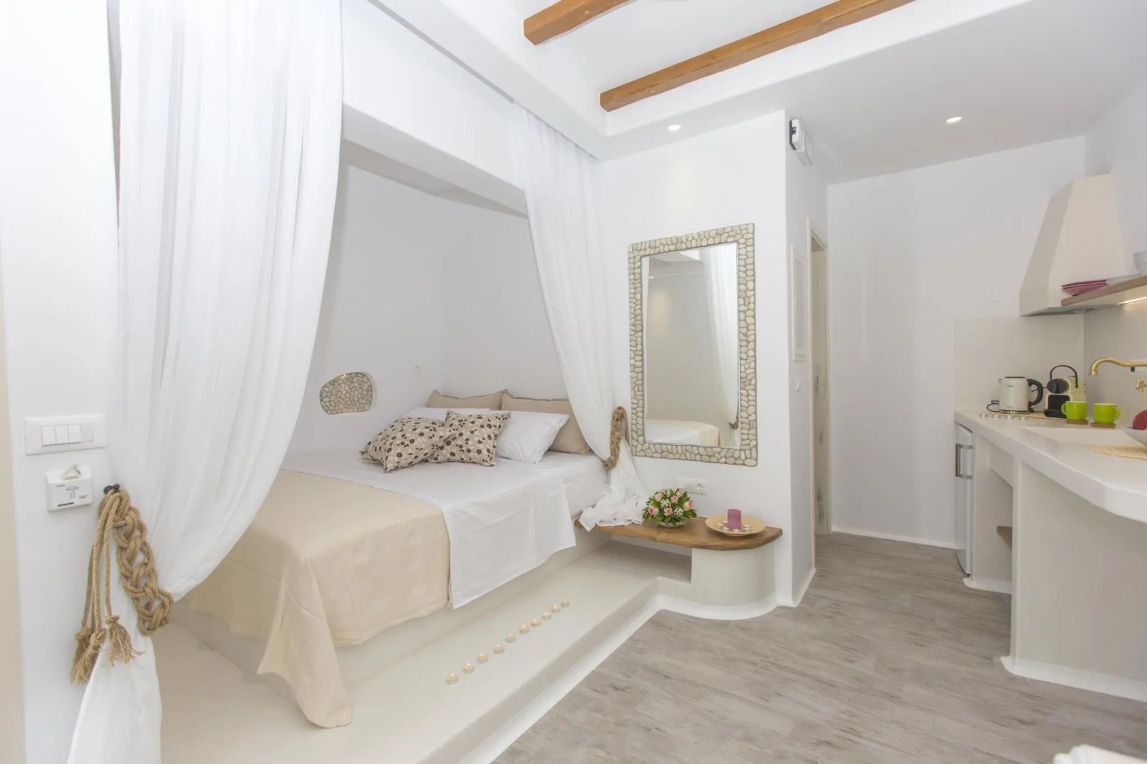 Helles Schlafzimmer mit podestartigem Bett, weißen Vorhängen und einem Wandspiegel