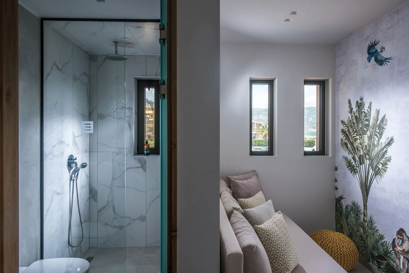 Blick in das moderne Badezimmer mit Dusche und Marmorwand neben einem Wohnbereich.