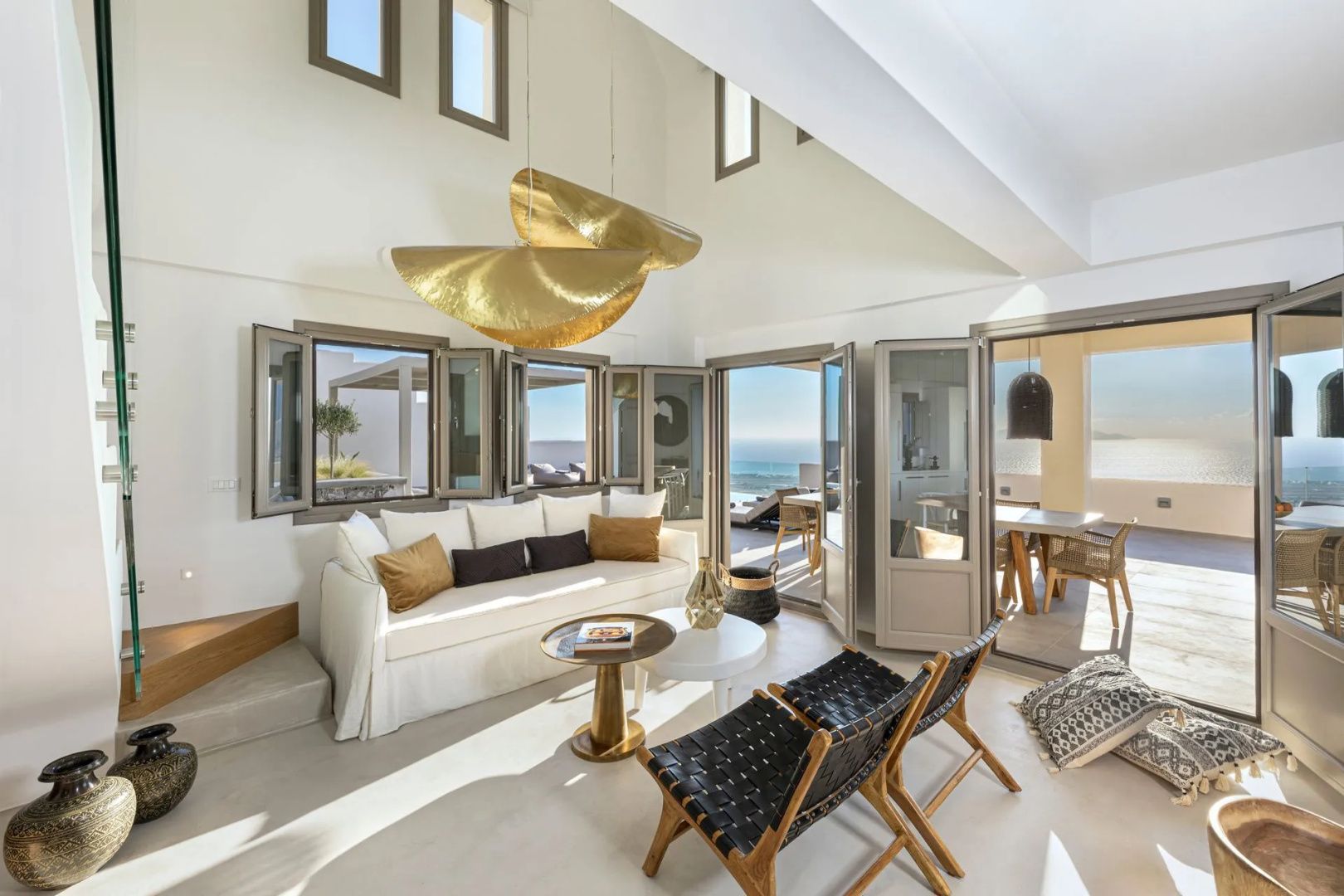 Helles Wohnzimmer mit weißem Sofa, goldenen Lampen und geöffneten Flügeltüren zur Terrasse.