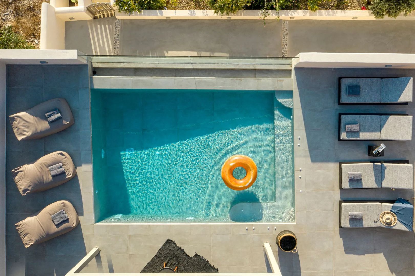 Draufsicht auf einen rechteckigen Swimmingpool mit klarem Wasser und einem gelb-orangen Schwimmring.
