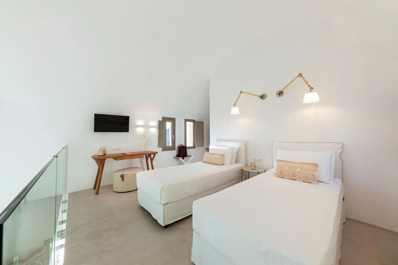 Weiß gestaltetes Schlafzimmer mit zwei Einzelbetten, Schreibtisch und Wandleuchten.